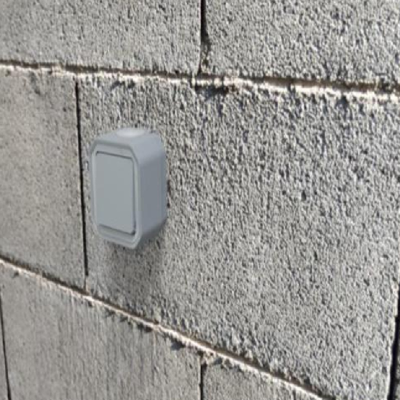 Conmutador estanco monobloc de superficie gris en muro